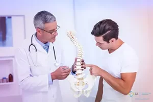 a doctor talking to a patient while holding a model of a spine