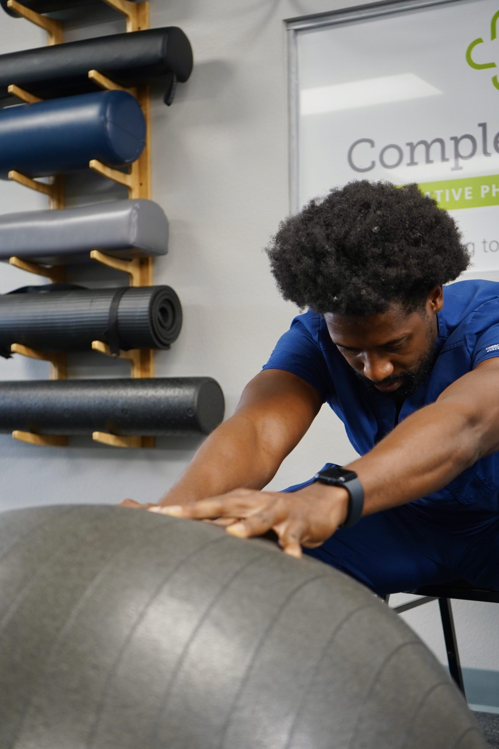 a clinican stretching with a grey yoga ball
