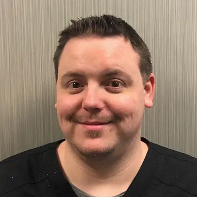 a man in a black scrub top is smiling for the camera