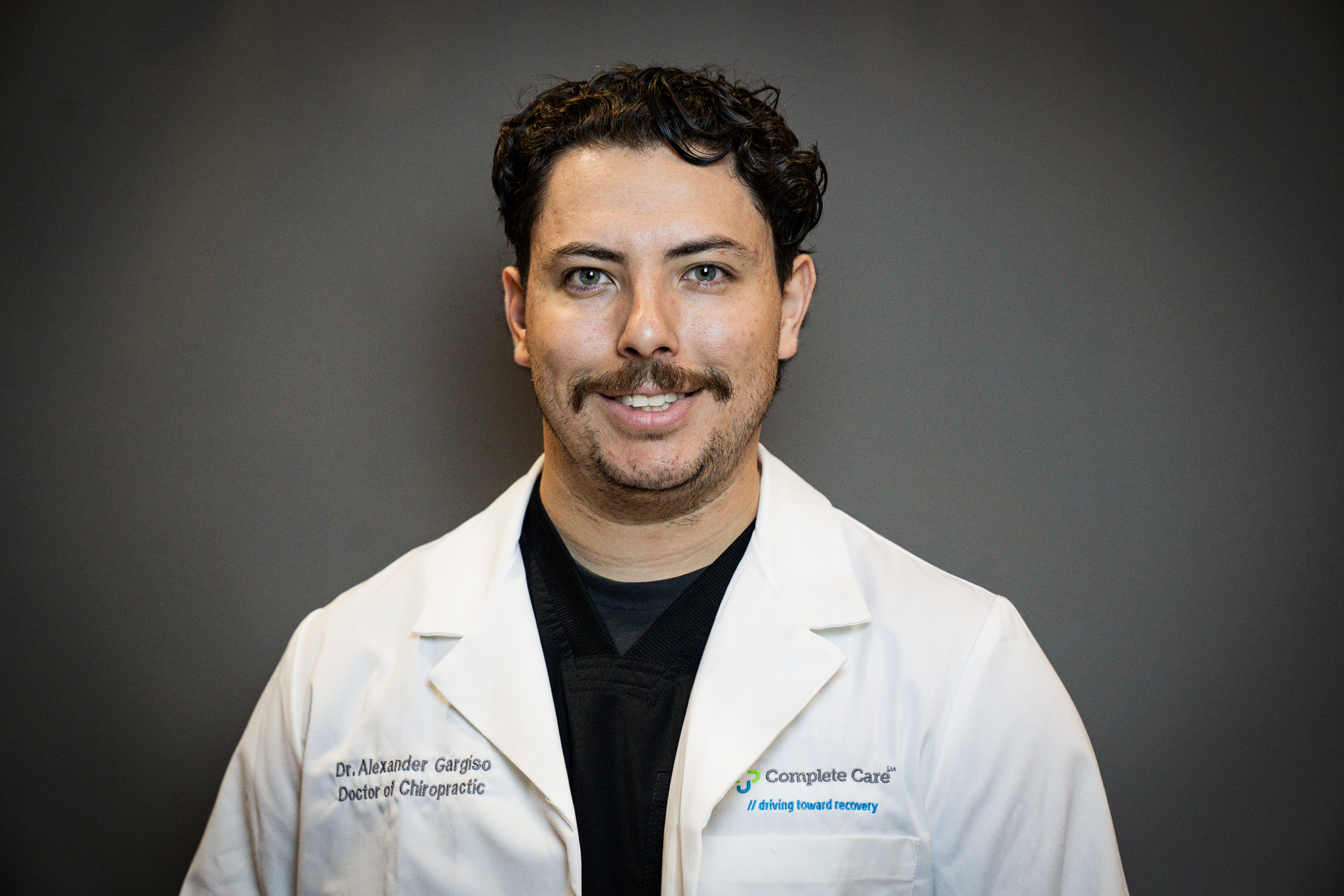 a man wearing a white lab coat that says complete care on it
