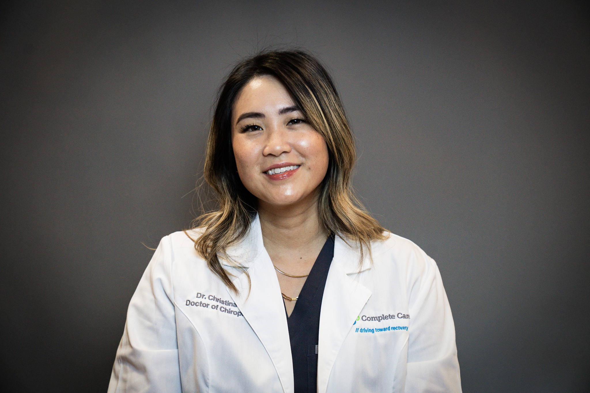 a woman wearing a lab coat that says complete care