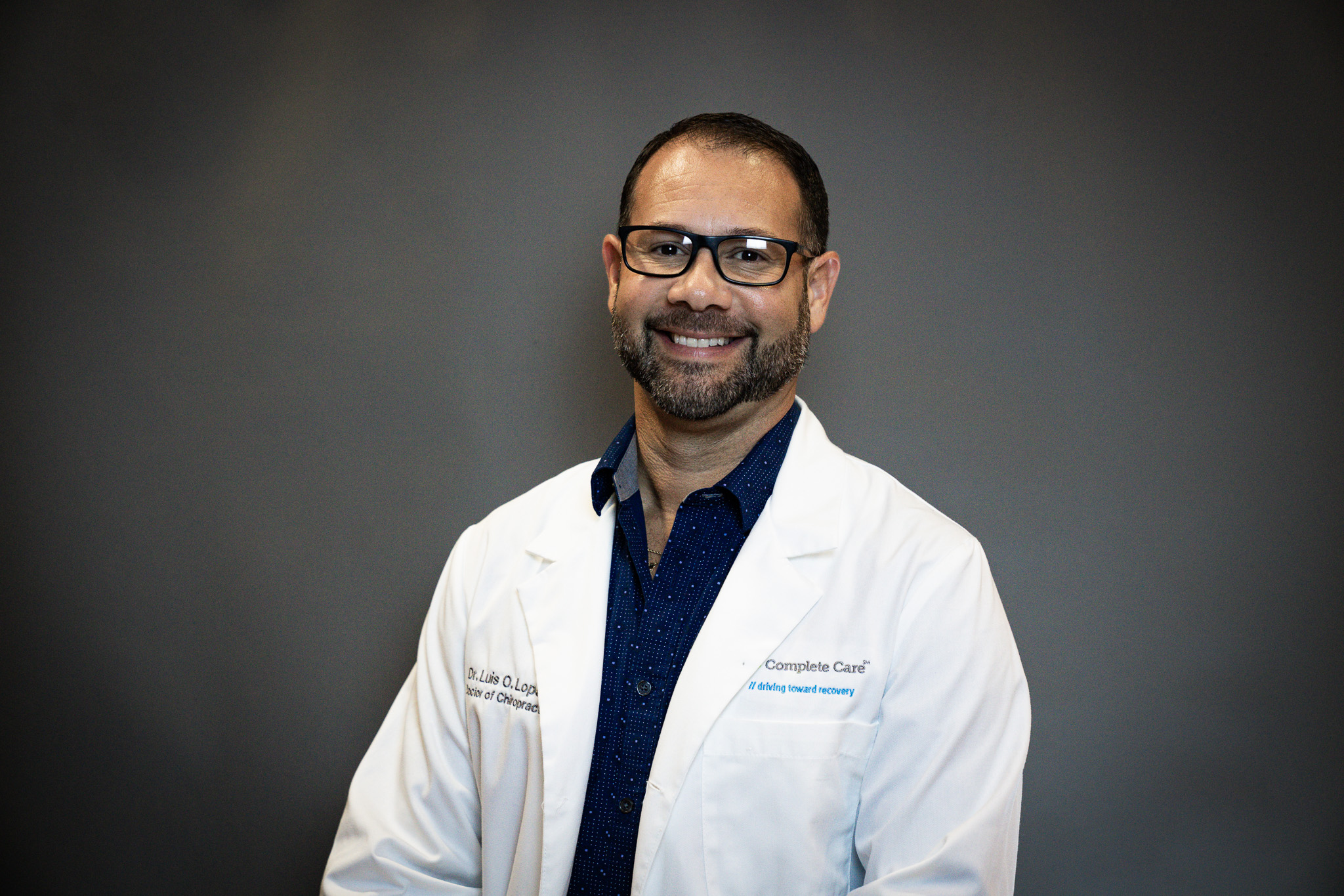 a man wearing a lab coat that says complete care