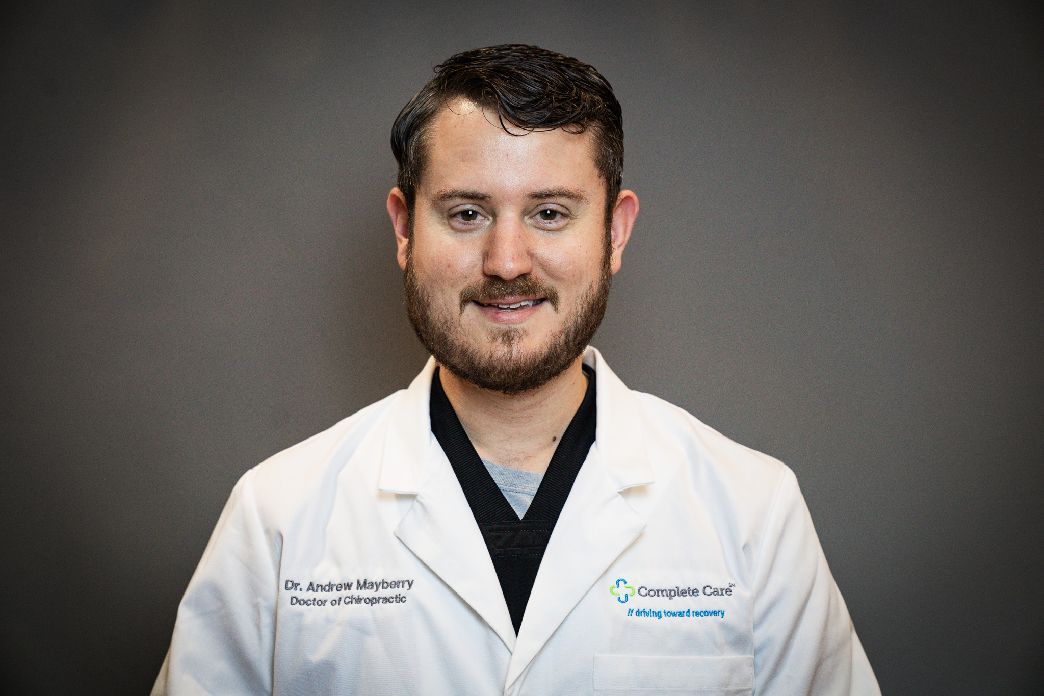 a man wearing a white lab coat that says complete care